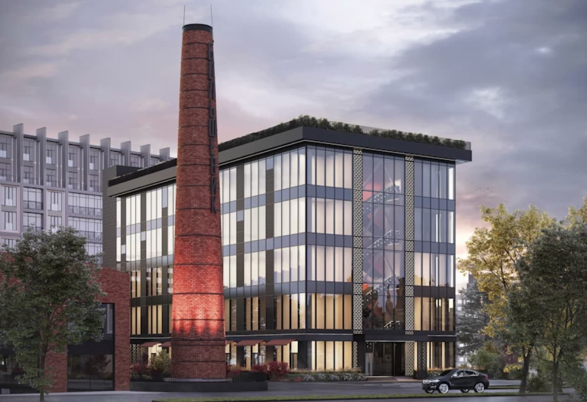 A glass-fronted office building beside a preserved brick chimney