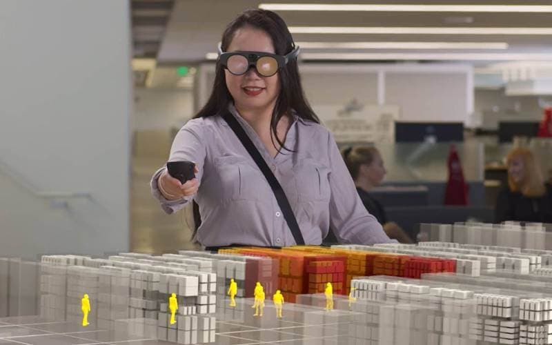 A person reviewing a scale model of a production layout laid out in blocks across a table.