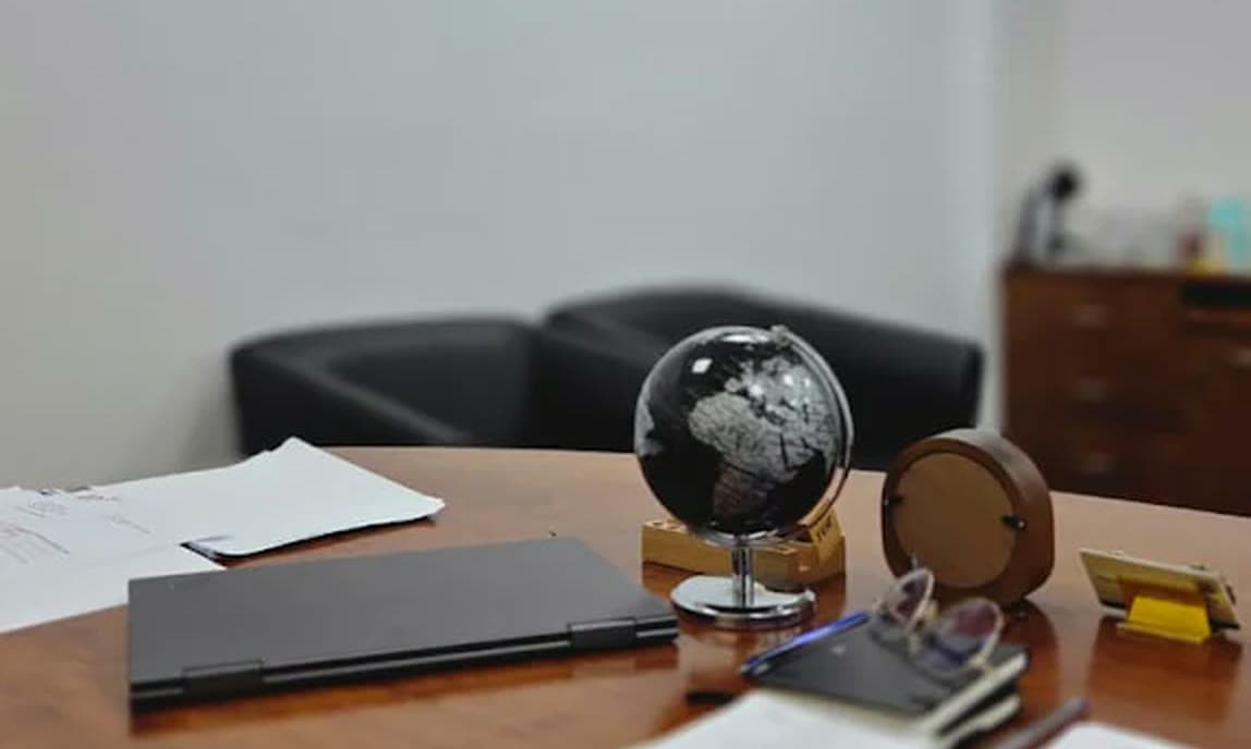 A desk in the MHBC office with a desk globe, a closed laptop and working papers.