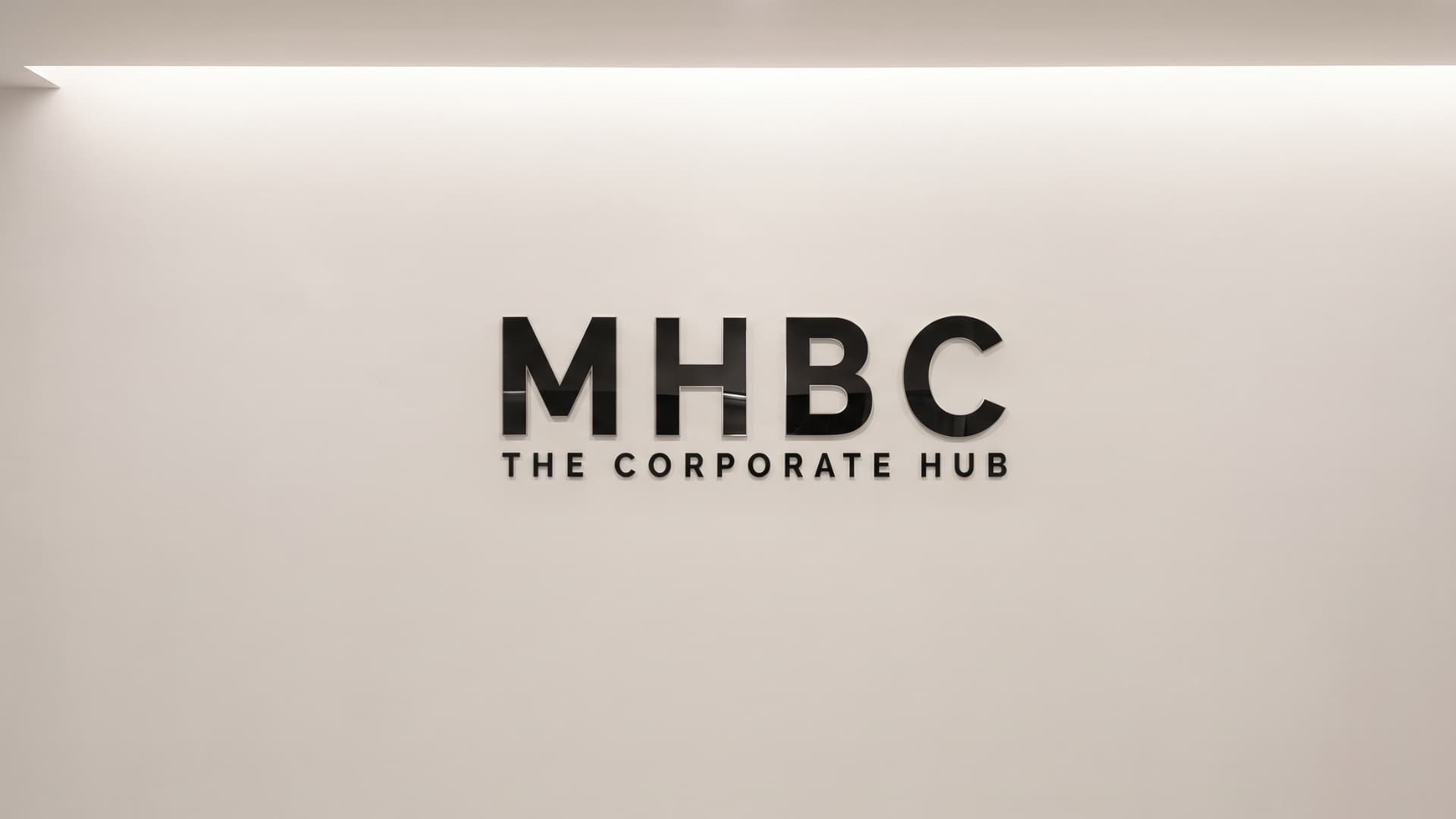 The MHBC wall sign, lit from above on a plain wall.