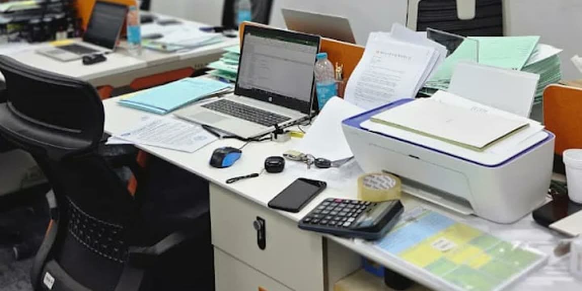Desks in the MHBC office with laptops, printed schedules, a printer and a calculator.
